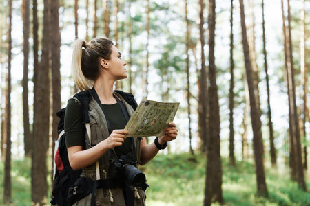 Female hiker with big backpack using map for orienteering in the forestの写真素材