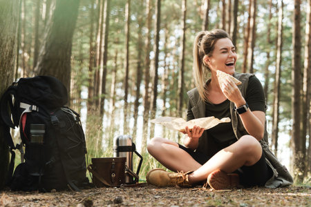 Female hiker during small halt eating sandwich in green forestの写真素材