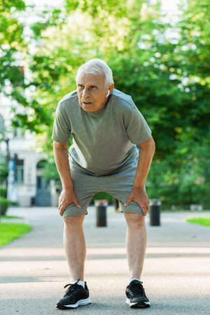 Exhausted elderly man after his jogging workoutの写真素材