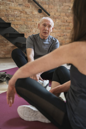 Active elderly people sitting on a exercising mats during fitness workoutの写真素材