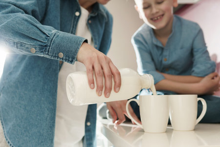 Mother and her cute son drinking milk on the kitchenの写真素材