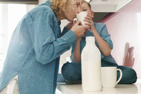Mother and her cute son drinking milk on the kitchenの写真素材