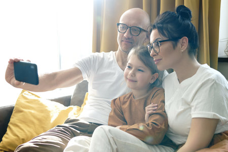 Happy family taking selfie using smartphone at homeの写真素材