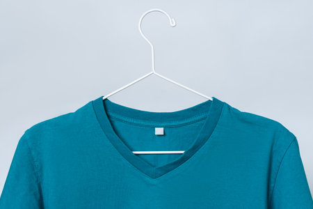Worn blue t-shirt hanging on a hanger against gray backgroundの写真素材