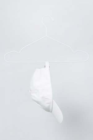 White baseball cap hanging on a hanger against gray backgroundの写真素材