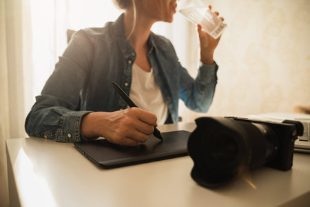 Woman photographer drinking still water on her workplace
