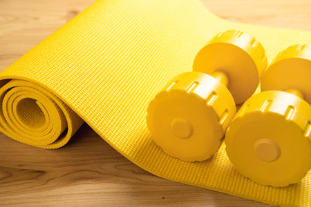 Yellow dumbbells and fitness mat on the floorの写真素材