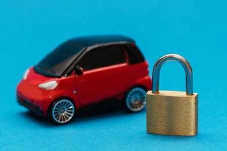 Yellow metallic padlock next to a red with black toy carの写真素材