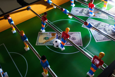 Table football game with US dollar bills scattered around it, alluding to a betting concept