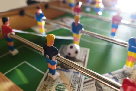 Table football game with US dollar bills scattered around it, alluding to a betting concept