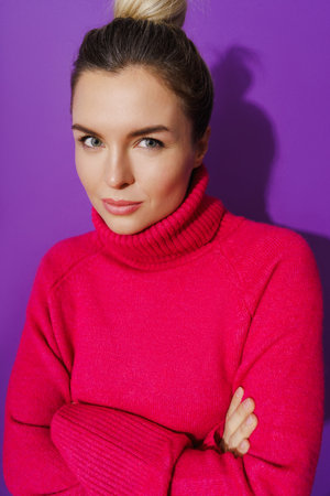 Suspicious woman wearing warm polo neck sweater against purple backgroundの写真素材