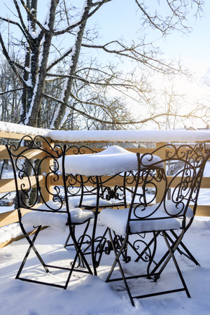 Outdoor table and chairs covered in snow after the first snowfallの写真素材