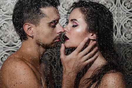Beautiful and sensual couple captured through wet glassの写真素材