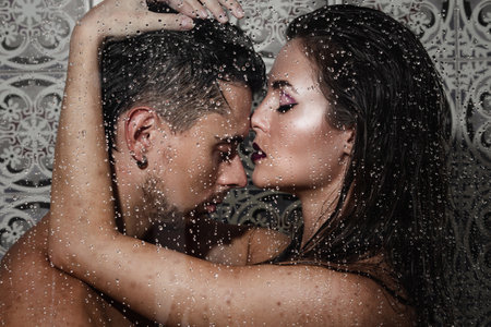 Beautiful and sensual couple captured through wet glassの写真素材