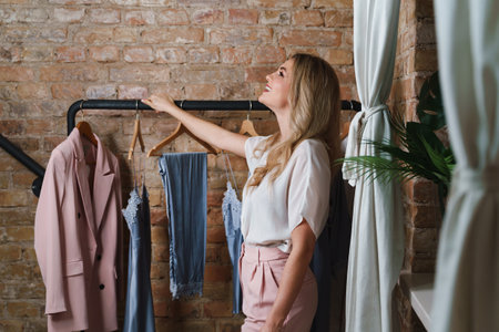 Young woman fashion designer and clothing rack with different outfitsの写真素材