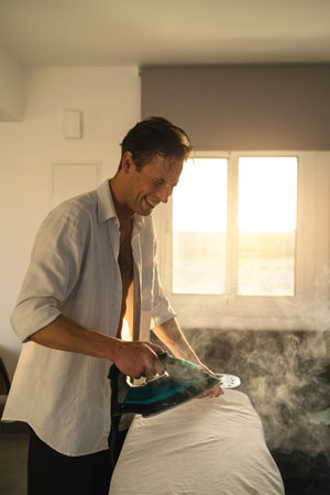 Portrait of single man ironing his clothes at homeの写真素材