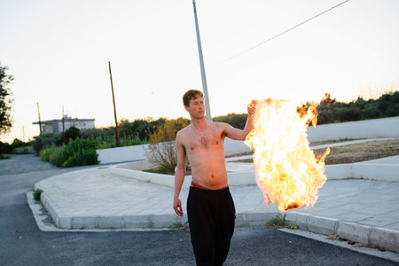 Adult man pyromaniac burning his shirt on the streetの写真素材