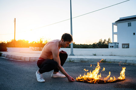 Adult man pyromaniac burning his shirt on the streetの写真素材