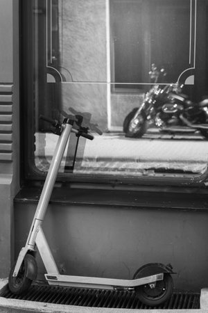 Small e-scooter and big motorcycle in window reflection. Concept of personal growth, life goals or self-acceptance.の写真素材