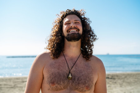 Cheerful curly man relaxing on the beach during sunny summer dayの写真素材