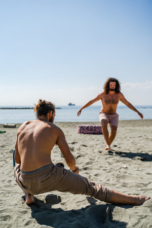 Two men warming up before workout on sandy beachの写真素材