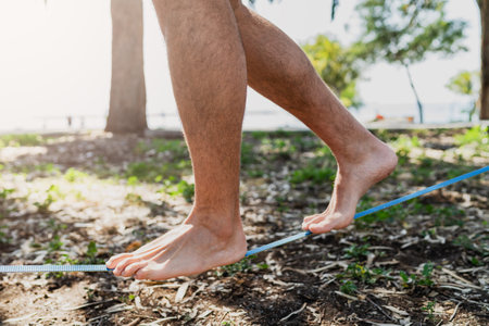 Male feet on slackline during slacklining in city parkの写真素材