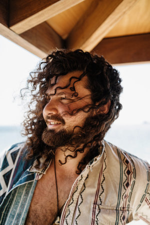 Carefree curly man relaxing on the beach during summer suny day
