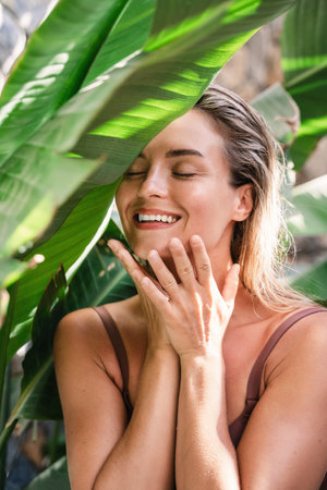 Beautiful and natural looking woman with tropical banana leavesの写真素材