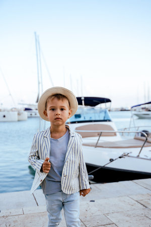 Cute stylish boy posing near yacht in marinaの写真素材