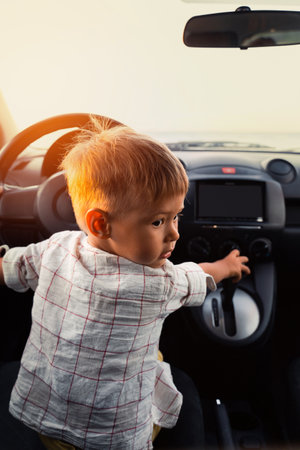 Cute little boy playing in car and acting like real adult driverの写真素材