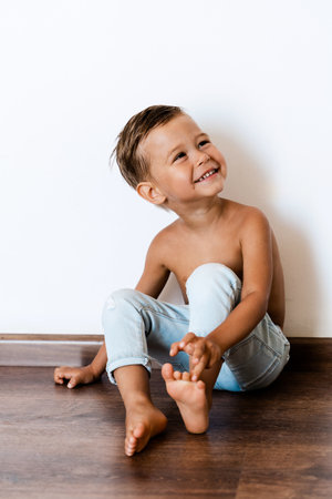 Happy cheerful little boy wearing jeans posing against white wallの写真素材