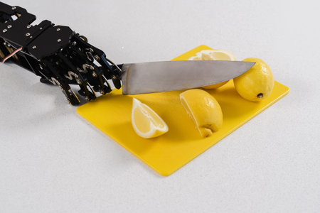 Real robots hand cutting lemons with sharp knife. Concept of robotic process automationの写真素材