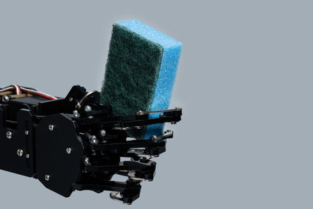 Real robots hand holding sponge for dishwashing against gray background