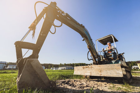 Young man operating his old excavator during his work on a construction siteの写真素材