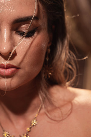 Portrait of stunning woman with wet hair effect, golden eyeshadows, and precise eyelinerの写真素材