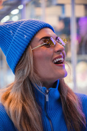 Woman, dressed in warm clothes and wearing sunglasses shaped like fire flames, is having fun in a amusement parkの写真素材