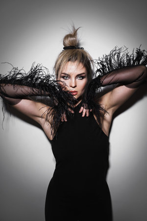 Fashion portrait of stunning woman wearing long tulle gloves with feather trims