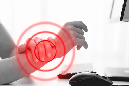 Woman working in office with a carpal tunnel syndrome or wrist joint inflammationの写真素材