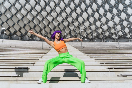 Active woman dancer wearing colorful sportswear performing on the street during summer dayの写真素材