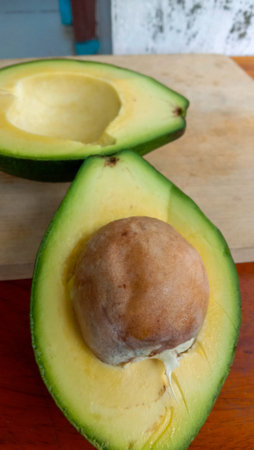 A photo of an avocado that has been split on a table