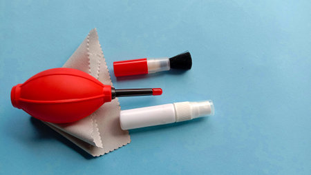 camera cleaning supplies such as blower, brush, microfiber cloth, water spray on a blue background