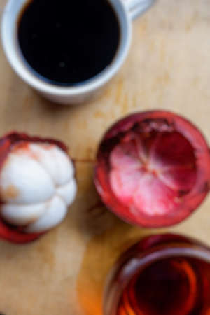 Blur photo of fresh mangosteen fruit and coffee on wooden table backgroundの写真素材
