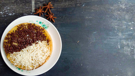 A mini photo of a martabak with a chocolate topping and grated cheese found a cup is hot, a knife, a...