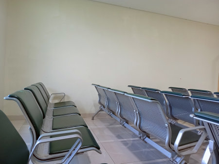 Modern public seating arrangement in a clean waiting area with empty metal and cushioned chairsの写真素材