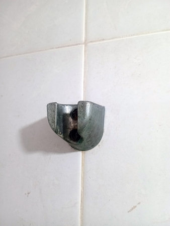 A metallic wall bracket attached on white tiled bathroom wall surfaceの写真素材