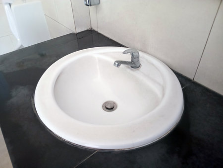A round washbasin with chrome faucet installed on a black bathroom countertopの写真素材