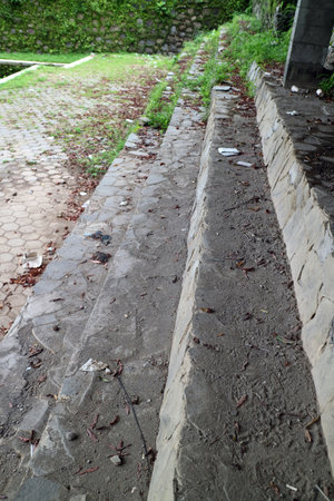 Dirty stone steps surrounded by grass, trash, and dried fallen leavesの写真素材