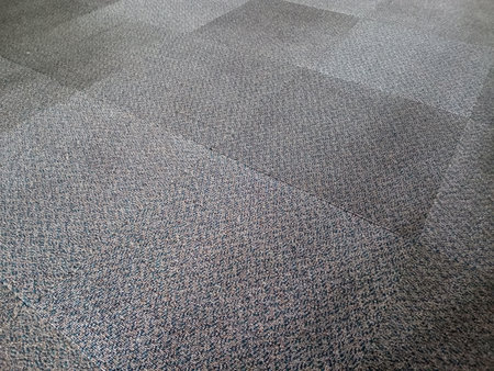 Floor covered in overlapping carpet tiles forming subtle grid layoutの写真素材