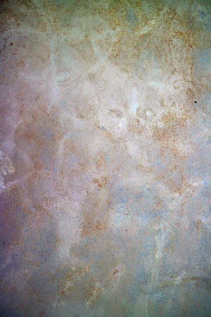 A textured wall surface with a subtle blend of light colors and faint patterns. The surface appears weathered with a mix of beige, cream, and light blue hues, creating an abstract appearance.の写真素材