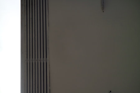 A minimalist view of a wall with vertical lines and a smooth surface, featuring a light gradient from white to gray. The composition emphasizes simplicity and modern design.の写真素材